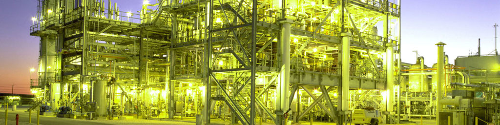 Close-up photograph of a LNG plant lit up at dusk 